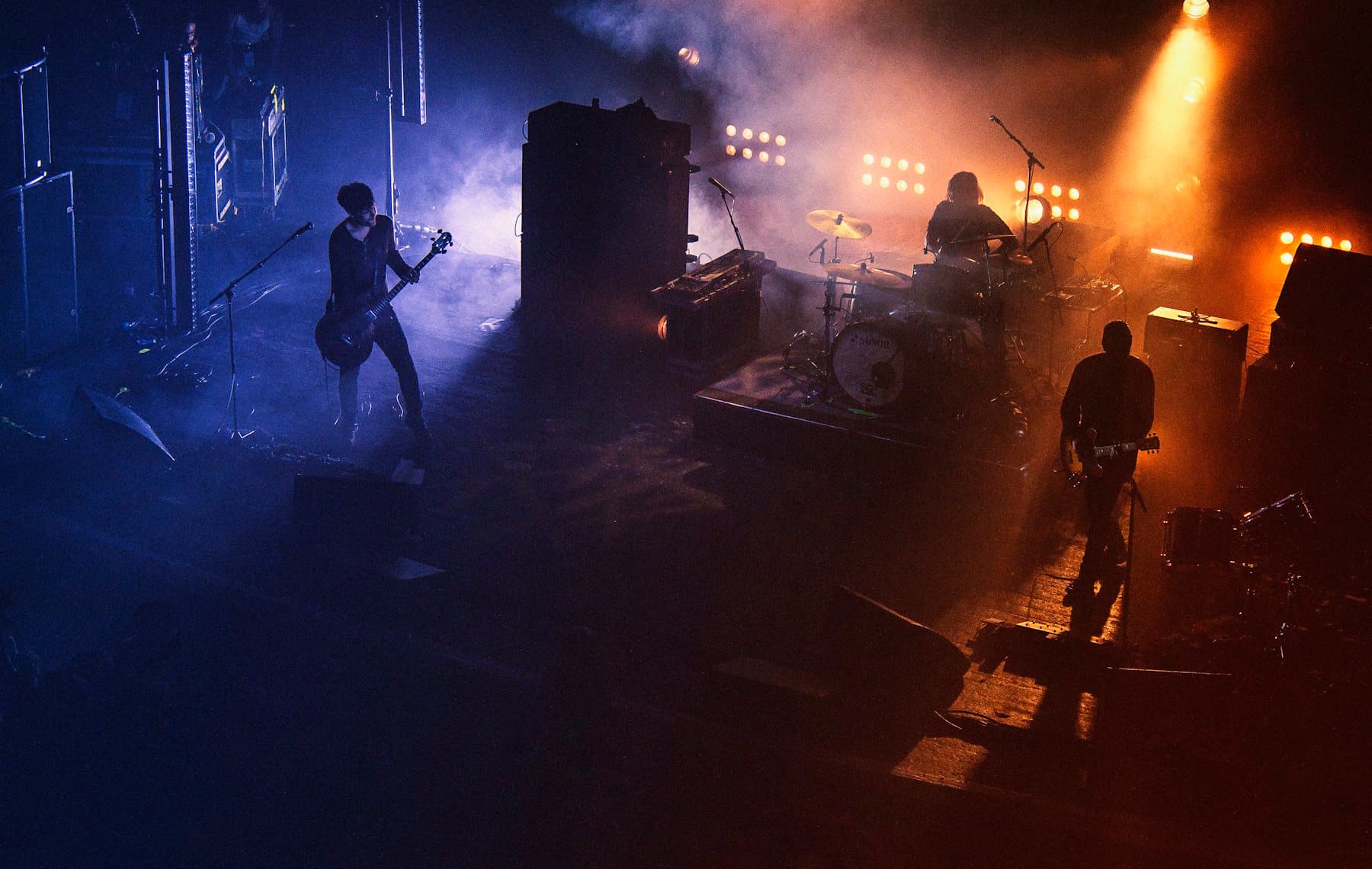 Band performing on a hazy stage under blue and amber lights
