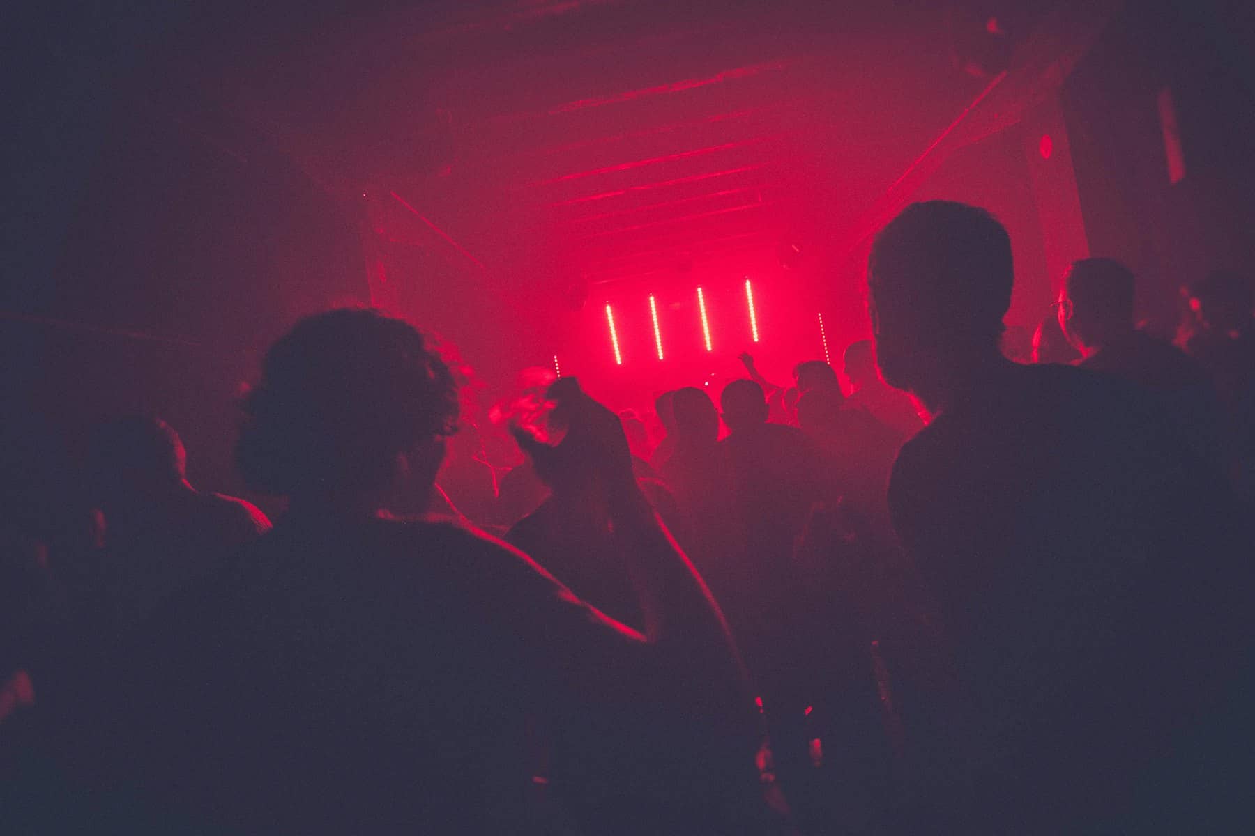 Silhouetted performers under red stage light